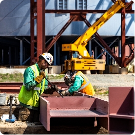 workers in hardhats working on a steel beam at the Mesabi Metallics site.